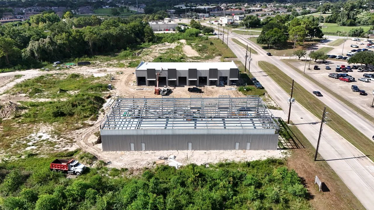 Day 170 aerial progress view showing exterior wall panels installed on the foreground building, exposed roof framing, and a second building shell in the background